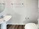 Bright bathroom featuring a pedestal sink, toilet, and towel rack with hardwood floors at 2005 Silent Bend Dr, Durham, NC 27704