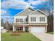 Charming two-story home with a stone-accented garage and covered porch, set against a blue sky at 219 E American Merigold Dr # 45, Benson, NC 27504