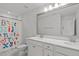 Bright bathroom with a double vanity, large mirror, and a shower with a playful alphabet curtain at 2534 Great Daisy Ln, New Hill, NC 27562