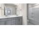 Bathroom featuring double sink vanity with gray cabinets and large mirror over white countertop and shower with tub at 257 Umstead St, Sanford, NC 27330