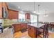 A kitchen with an island with granite countertops, wooden cabinets, stainless steel appliances, and an adjacent dining area at 29 Alban Row, Fuquay Varina, NC 27526