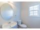 Bright bathroom featuring a pedestal sink, oval mirror, and a window at 3671 Coach Lantern Ave, Wake Forest, NC 27587