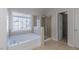 Bright bathroom featuring a large window, soaking tub, and glass-enclosed shower at 3671 Coach Lantern Ave, Wake Forest, NC 27587