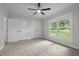 Bright bedroom featuring a ceiling fan, neutral carpet and paint, and double closets with a sunlit window at 4705 Bernie Pl, Raleigh, NC 27616