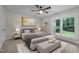 Comfortable bedroom featuring a ceiling fan, neutral color palette, carpet floors, and a large window overlooking greenery at 4705 Bernie Pl, Raleigh, NC 27616