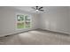 Bright bedroom features neutral carpet, a ceiling fan, and a large window with views of the lawn at 4705 Bernie Pl, Raleigh, NC 27616