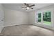 A spacious and airy bedroom featuring a window with backyard views and a ceiling fan at 4705 Bernie Pl, Raleigh, NC 27616