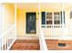 Close up of yellow home front porch with white railings and brick steps leading to the front door at 5748 Presentation St, Knightdale, NC 27545