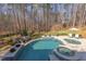 Backyard in-ground pool with integrated spa and stone surround, alongside wooded perimeter at 6105 Valencia Ct, Raleigh, NC 27614