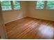 Empty bedroom with hardwood floors and natural light from two windows at 703 Caswell Rd, Chapel Hill, NC 27514