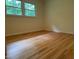 A light-filled bedroom with hardwood floors and window views of the lush greenery outside at 703 Caswell Rd, Chapel Hill, NC 27514