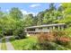 Charming home featuring large windows, brick accents, and lush landscaping, surrounded by mature trees at 703 Caswell Rd, Chapel Hill, NC 27514