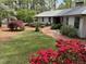 Inviting home exterior with lush landscaping, flowering bushes, and a charming brick walkway at 723 Chelsea Dr, Sanford, NC 27332