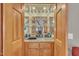 Home wet bar area with tile countertop, sink, mirrored backsplash, and glass storage at 723 Chelsea Dr, Sanford, NC 27332