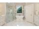 Bright bathroom featuring marble floors, soaking tub beneath a window, and a glass-enclosed shower at 7800 Twin Pines Way, Fuquay Varina, NC 27526