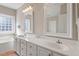 Elegant bathroom with double sinks, white cabinetry, decorative mirrors, and a window bringing in lots of natural light at 8513 Barrett Hall Ln, Wake Forest, NC 27587