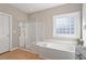 Bright bathroom featuring a soaking tub, glass-enclosed shower, neutral walls, and natural light from block window at 8513 Barrett Hall Ln, Wake Forest, NC 27587