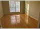 Bedroom features hardwood flooring, a large window letting in natural light, and neutral colored walls at 100 W Acres Cres, Cary, NC 27519