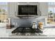 A close-up of a stove and microwave in a kitchen with white cabinets and gray backsplash at 10040 Ward, Chapel Hill, NC 27517
