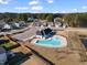 Aerial view of a community pool with an attached clubhouse, parking, and nearby residential area at 1008 Sandtrap Way, Durham, NC 27703