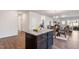 Kitchen island featuring granite countertops, dark wood cabinets, and an open view into the dining and living areas at 1008 Sandtrap Way, Durham, NC 27703