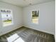 Cozy bedroom with ample natural light from two windows, and neutral carpet at 108 Torain St, Hillsborough, NC 27278