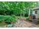 Lush backyard with a wooden retaining wall, stone pathway, and a grill on the wooden deck at 109 Reton Ct, Cary, NC 27513