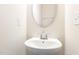A simple powder room with a pedestal sink, oval mirror, and neutral decor at 1154 Romeria Dr, Durham, NC 27713