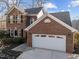 Two-story brick home with a two-car garage and mature landscaping under a partly cloudy sky at 118 N Drawbridge Ln, Cary, NC 27513