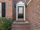 Close-up of the front door with brick steps, traditional hardware, and decorative lighting at 118 N Drawbridge Ln, Cary, NC 27513