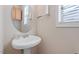 Powder room featuring white pedestal sink with chrome hardware and round mirror with overhead light fixture at 1324 Vanagrif Ct, Wake Forest, NC 27587