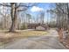 Secluded home featuring a long driveway surrounded by many trees on a partly cloudy day at 145 Traceway N, Sanford, NC 27332