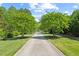 Trees line a grand driveway approach to the estate, with landscaping and grass on either side at 219 Colvard Park Dr, Durham, NC 27713