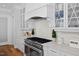 White kitchen has stainless oven, stone countertops, a tile backsplash, and custom cabinetry at 219 Colvard Park Dr, Durham, NC 27713