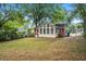 Backyard showcasing sunroom addition with large windows, a brick section, and mature trees at 2453 Derby Dr, Raleigh, NC 27610