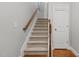 A carpeted staircase with wooden banister and a white door at the top of the stairs at 3003 Weston Green Loop, Cary, NC 27513