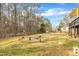 Large, grassy backyard features a fire pit and playset surrounded by mature trees, ideal for outdoor fun at 305 November St, Garner, NC 27529