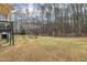 Large backyard featuring a firepit area, playhouse, and mature trees at 305 November St, Garner, NC 27529