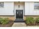 Inviting front door with a welcome mat, framed by lush greenery and modern exterior lighting at 305 November St, Garner, NC 27529