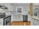 Kitchen features stainless appliances, white subway tile backsplash, white cabinets, and hardwood floors at 305 November St, Garner, NC 27529