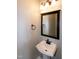A modern half bathroom with a pedestal sink, decorative mirror, and updated fixtures at 309 Mainline Sta, Morrisville, NC 27560