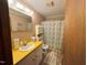 A functional bathroom with a yellow countertop, a white sink, and a shower with a curtain at 322 Blackstone Rd, Sanford, NC 27330
