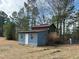 Exterior shot of a weathered blue and green outbuilding with a white door at 322 Blackstone Rd, Sanford, NC 27330