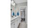 Bright bathroom featuring a white vanity with a marble countertop, sink and a view to the tiled shower at 3460 Willow Green Dr, Apex, NC 27502