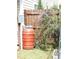 Backyard area featuring an orange rain barrel near a wooden fence with overgrown vegetation at 401 Lawton Dr, Haw River, NC 27258