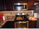 Kitchen with black stove, stainless steel microwave, and tile backsplash at 401 Lawton Dr, Haw River, NC 27258
