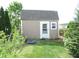 Backyard shed for extra storage with a gray roof, white door, and surrounded by green lawn at 401 Lawton Dr, Haw River, NC 27258