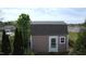 Aerial view of a backyard shed with a gray roof, white door, and surrounded by green trees at 401 Lawton Dr, Haw River, NC 27258