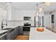 Modern kitchen featuring stainless steel appliances, white cabinets, gray lower cabinets and an island with seating at 405 Braxman Ln, Holly Springs, NC 27540