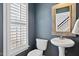 Well-lit powder room with dark blue walls, a pedestal sink, and a window with blinds at 405 Braxman Ln, Holly Springs, NC 27540